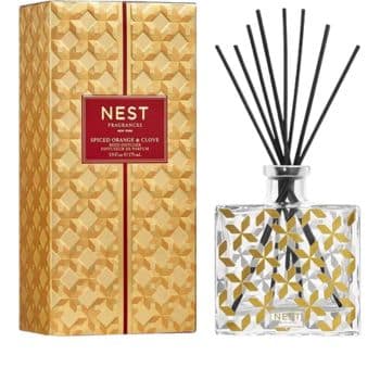 A Nest Fragrances Spiced Orange & Clove reed diffuser with a gold-patterned box and a matching glass bottle holding black diffuser sticks.