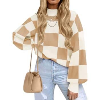 Woman wearing a beige and white checkered sweater, light ripped jeans, a beige shoulder bag, and layered necklaces. Her long wavy hair is loose. Only her upper body is visible.