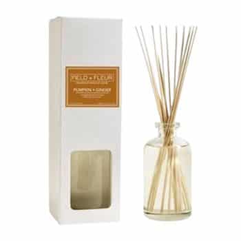 A glass diffuser bottle with thin reeds next to a white box labeled “Field + Fleur Pumpkin + Ginger.” The box has a small window showing the bottle inside.