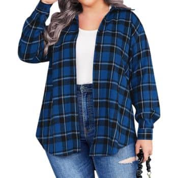 A person wearing a blue and black plaid shirt over a white top and ripped blue jeans stands holding a black hair scrunchie, with long wavy gray hair.