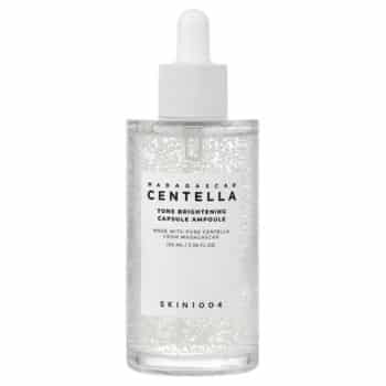 A clear dropper bottle labeled “Madagascar Centella Tone Brightening Capsule Ampoule” by SKIN1004, containing a transparent liquid with visible small capsules inside.