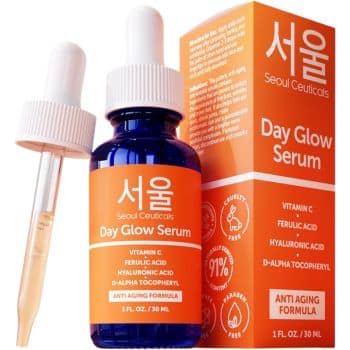 A blue bottle of Seoul Ceuticals Day Glow Serum with a dropper and its orange box. The box lists ingredients like vitamin C and hyaluronic acid, and features anti-aging formula and cruelty-free icons.
