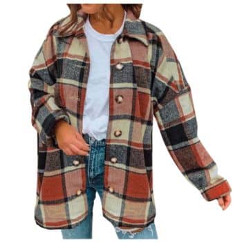A woman wearing a white t-shirt, blue jeans, and an oversized plaid flannel jacket with red, beige, and black tones stands with one hand in her pocket.