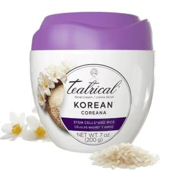 A white and purple container of Teatrical Korean facial cream with rice, white flowers, and loose rice grains beside it. The label mentions stem cells and rice.
