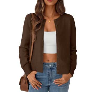 Woman wearing a brown button-up cardigan over a white crop top, blue jeans, and a brown shoulder bag, with loose wavy brown hair and a gold necklace.