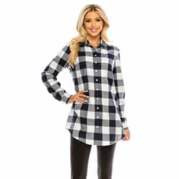 Woman wearing a long-sleeve black and white plaid button-up shirt and black pants, standing and smiling against a white background.