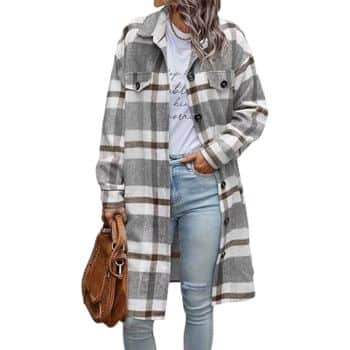 Woman wearing a long plaid coat over a white shirt and light blue jeans, holding a brown handbag in her left hand. Her hair is styled in loose waves. The background is white.