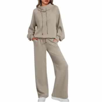Woman wearing a loose-fitting beige lounge set with long sleeves and wide-leg pants, hands in pockets, paired with white sneakers.