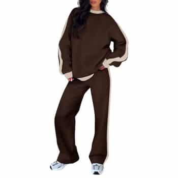 A person wearing a loose-fitting brown tracksuit with beige stripes on the sleeves and pants, paired with white sneakers, stands against a white background. Their head is only partially visible.