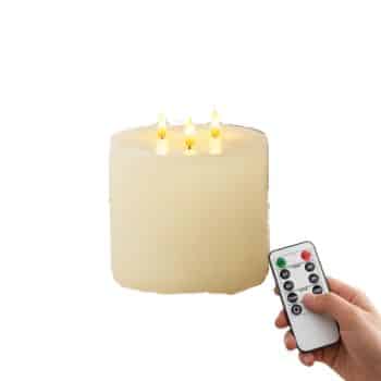 Large ivory three-wick flameless pillar candle with remote control styled with lace, pearls, and white flowers.