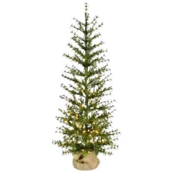 A slim artificial Christmas tree with sparse branches, decorated with small white lights, stands in a burlap-wrapped base against a plain background.