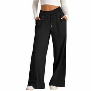 A person wearing a white long-sleeve crop top and loose-fitting black drawstring sweatpants with pockets, standing with hands in pockets.