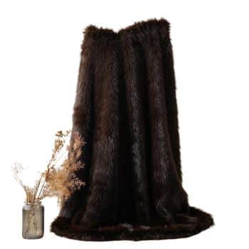 Dark chocolate brown faux fur throw blanket draped over a natural branch with dried fall flowers nearby.