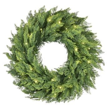 A green wreath made of pine branches with small, warm white lights evenly spaced throughout.
