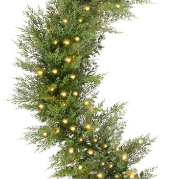 Green pine garland decorated with small warm white string lights, creating a festive and cozy holiday atmosphere. The garland appears lush and natural, with lights evenly distributed throughout.