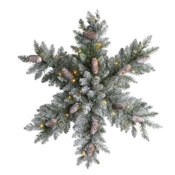 A decorative snowflake-shaped wreath made of frosted pine branches, pine cones, and small warm white lights, viewed from above against a white background.