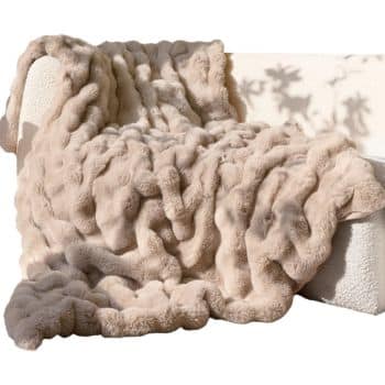 Soft beige faux fur throw blanket draped over a cream sofa in a warm sunlit living room.