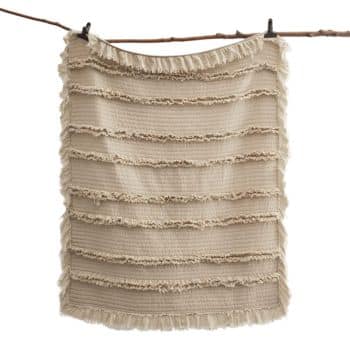 Cream pre-washed quilted boho throw blanket with textured fringe details displayed against a neutral wall.