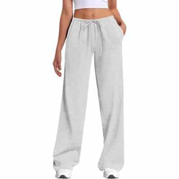 A person wearing light gray, loose-fitting sweatpants with pockets and a drawstring waist, paired with a white crop top and white sneakers. Only the lower body is visible.