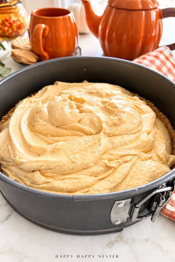 Thick pumpkin cheesecake filling added to a graham cracker crust in a springform pan.