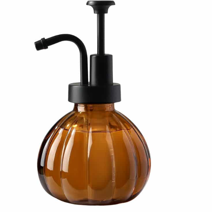 A brown, pumpkin-shaped glass pump bottle with a black top and spout, designed for dispensing liquid, shown on a white background.