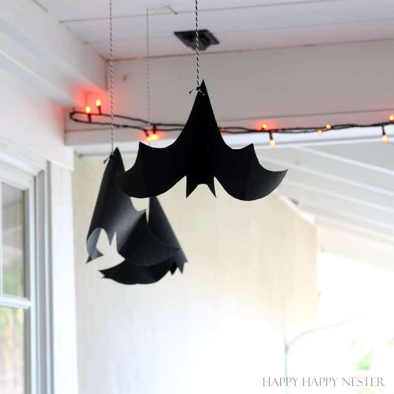 Hanging black paper bats with orange lights, one of these cute Halloween ideas for decorating a covered porch.