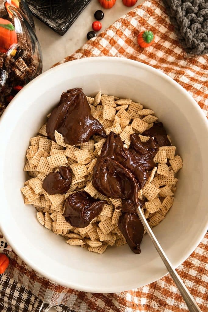 Chex cereal in a white bowl with dollops of melted chocolate on top