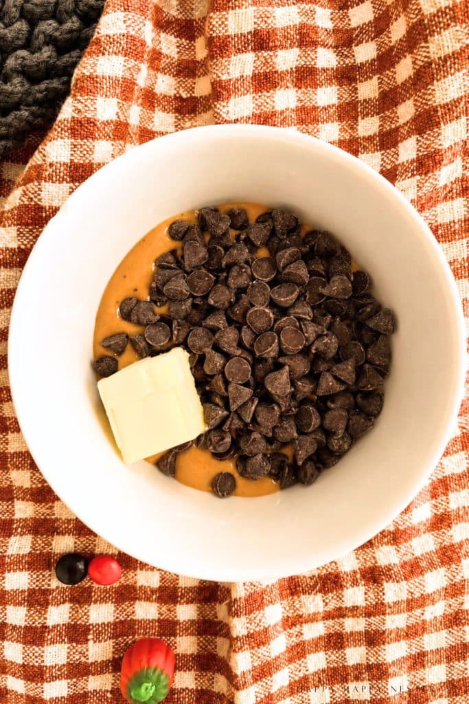Chocolate chips, peanut butter, and a pat of butter in a bowl before melting