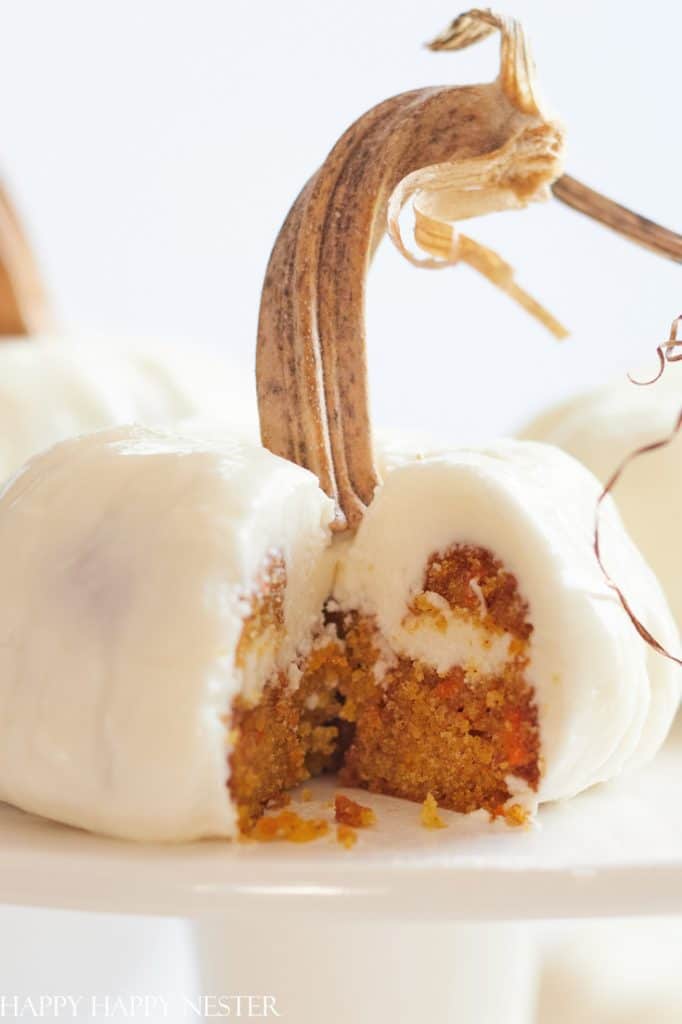 A pumpkin-shaped cake covered in white frosting, with a real pumpkin stem on top and a slice cut out to reveal orange cake inside—perfect for halloween food inspiration.