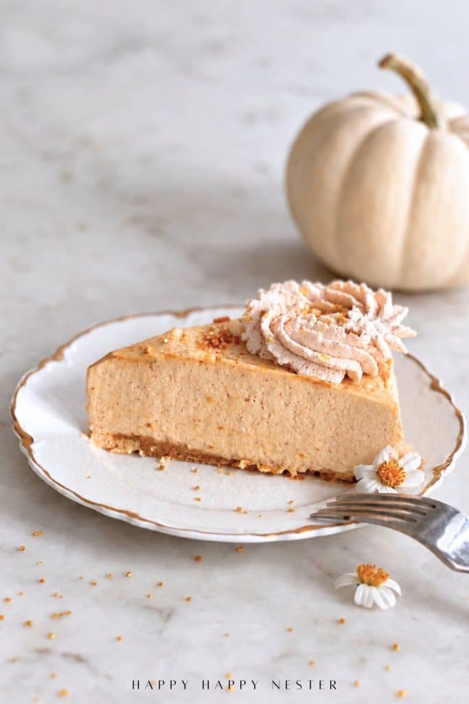 Slice of creamy no bake pumpkin cheesecake with graham cracker crust and spiced whipped cream.