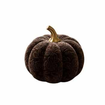 Dark brown embossed velvet pumpkin with a gold stem styled on a rustic wood table with autumn leaves and acorns.