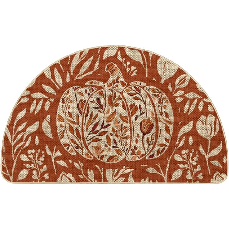 A semicircular mat with a large pumpkin design in the center, decorated with intricate floral and leaf patterns in shades of brown and beige.