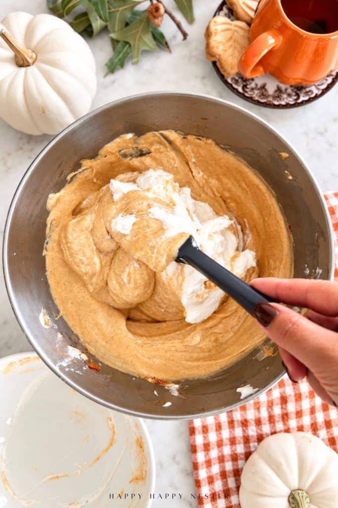 Folding whipped cream into pumpkin cheesecake filling for a no bake pumpkin cheesecake recipe.