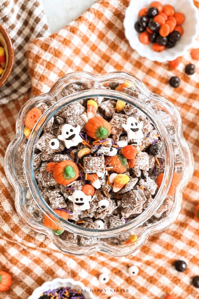 Halloween puppy chow with chocolate Chex cereal, candy corn, candy pumpkins, ghost candies, sprinkles, and candy eyes.