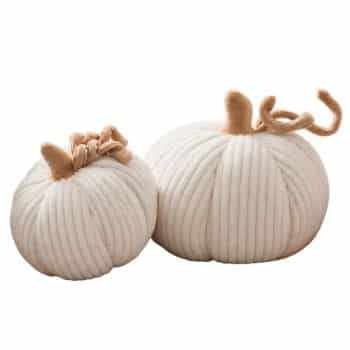Two large white ribbed fabric pumpkins styled with colorful fall leaves