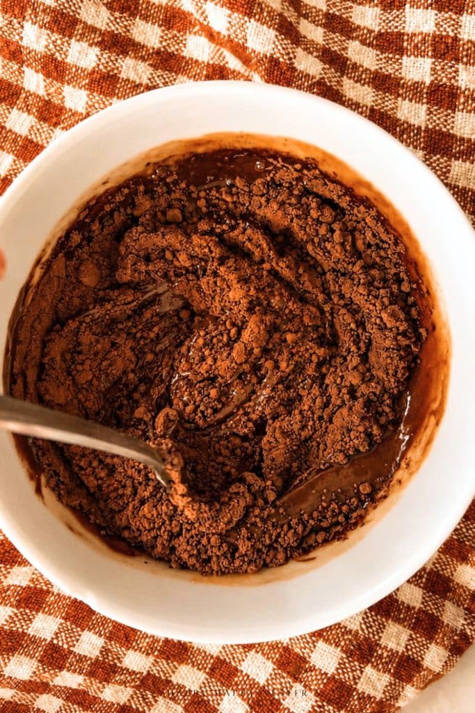 Melted chocolate and peanut butter mixture topped with cocoa powder, ready to stir