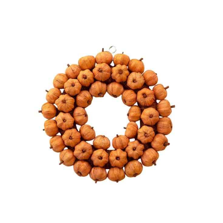 A wreath made of small, orange mini pumpkins arranged in two circular layers, set against a white background.