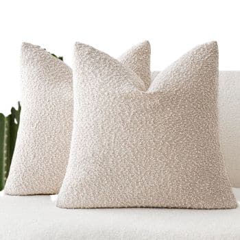 Neutral cream bouclé throw pillows with a nubby textured surface styled on a sofa.
