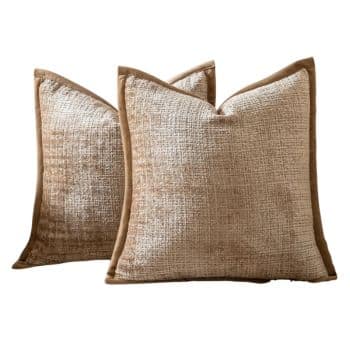 Neutral beige textured chenille throw pillows with soft brown velvet trim on a cream sofa.