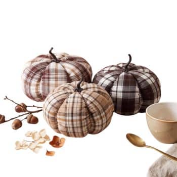 Three neutral plaid fabric pumpkins in brown, cream, and beige styled with acorns and dried flowers.