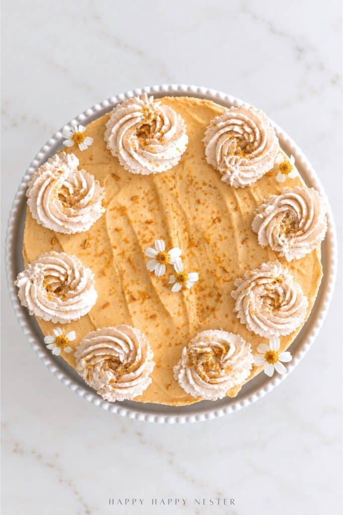 Overhead view of no bake pumpkin cheesecake topped with cinnamon whipped cream rosettes, edible flowers, and gold sprinkles.