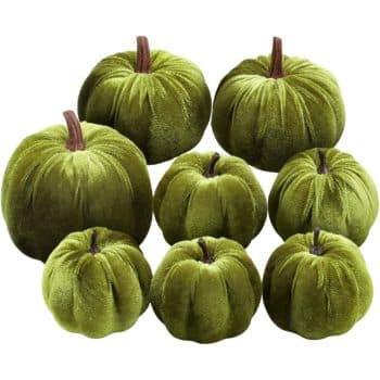 Set of eight olive green velvet pumpkins in assorted sizes with brown stems for fall decorating.