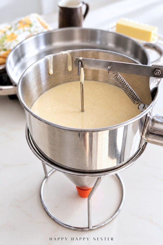 Homemade pancake batter in a stainless steel pancake dispenser ready for cooking