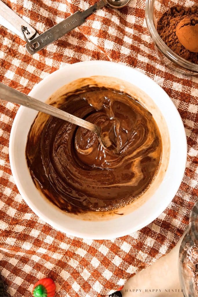 Peanut butter swirled into melted chocolate in a glass bowl