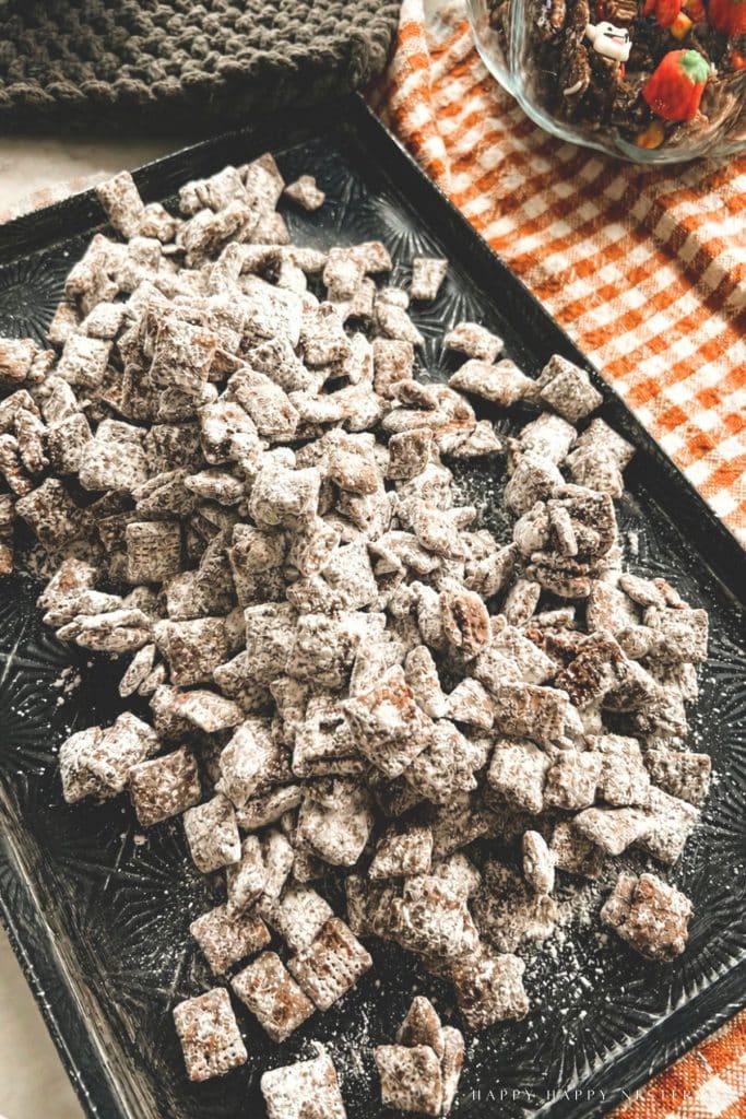 Chex cereal coated in powdered sugar spread on a tray to cool