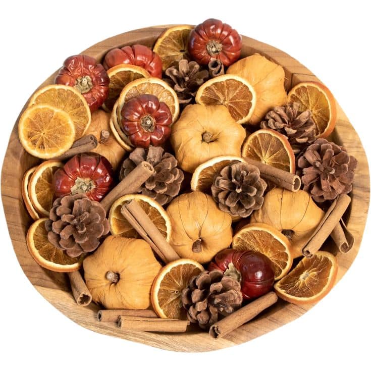 A wooden bowl filled with dried orange slices, small dried pumpkins, pinecones, and cinnamon sticks, arranged as a decorative autumn potpourri.