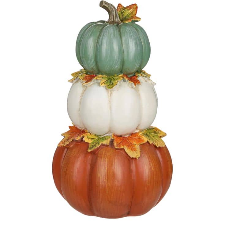 Three stacked pumpkins in green, white, and orange, separated by clusters of autumn leaves, forming a decorative fall arrangement.