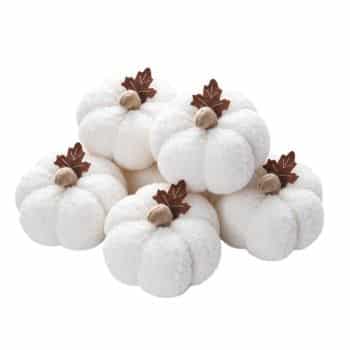 Five small white fuzzy fabric pumpkins with brown stems and leaves