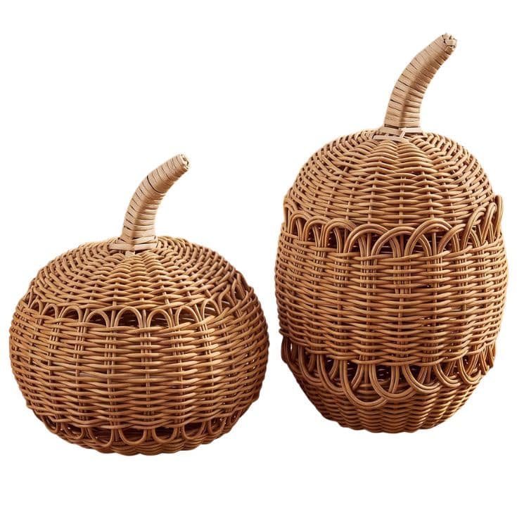 Two round, lidded baskets made of woven wicker with curved handles on top, resembling pumpkins or gourds, placed side by side against a white background.