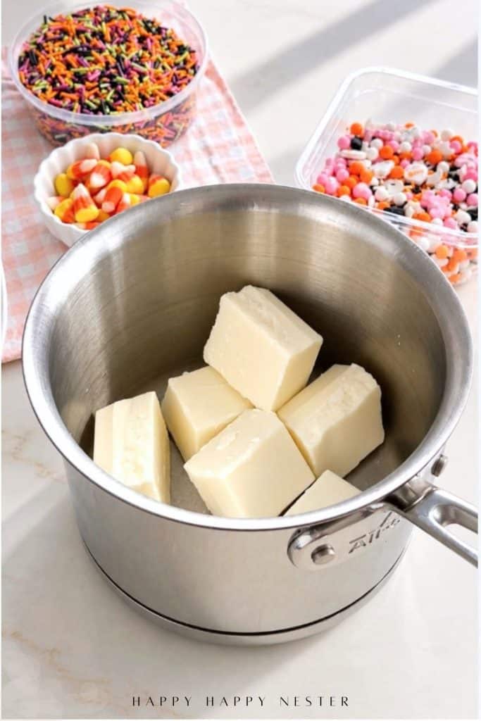 Pieces of white almond bark in a stainless steel saucepan.